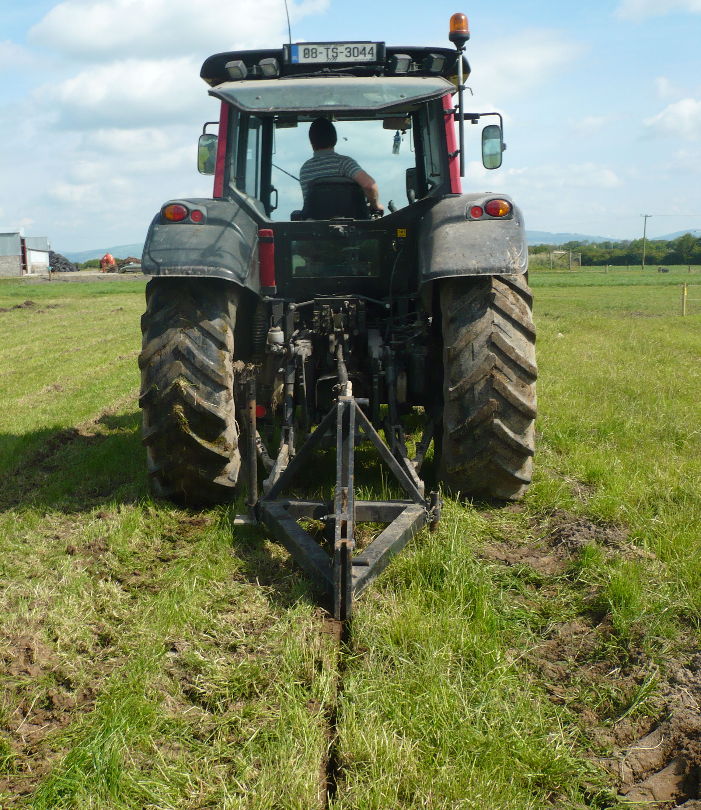 A tractor pulling a mole plow.